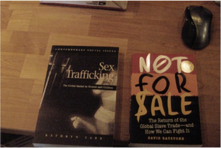 Two sex trafficking books photographed on a desk — never documented in place, never collected as evidence